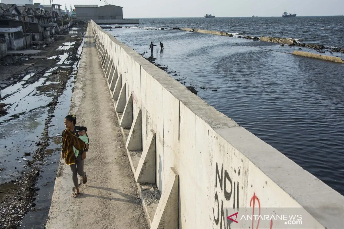 Warga berjalan kaki melintasi tanggul di kawasan pesisir Muara Baru, Penjaringan, Jakarta, Senin (15/5/2017). Foto: Antara Foto/Aprillio Akbar/pras.